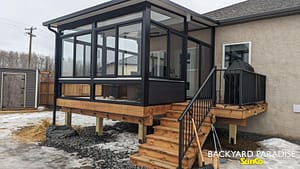 Black studio sunroom with treated wood deck and black aluminum railings, Stonewall, Manitoba 1